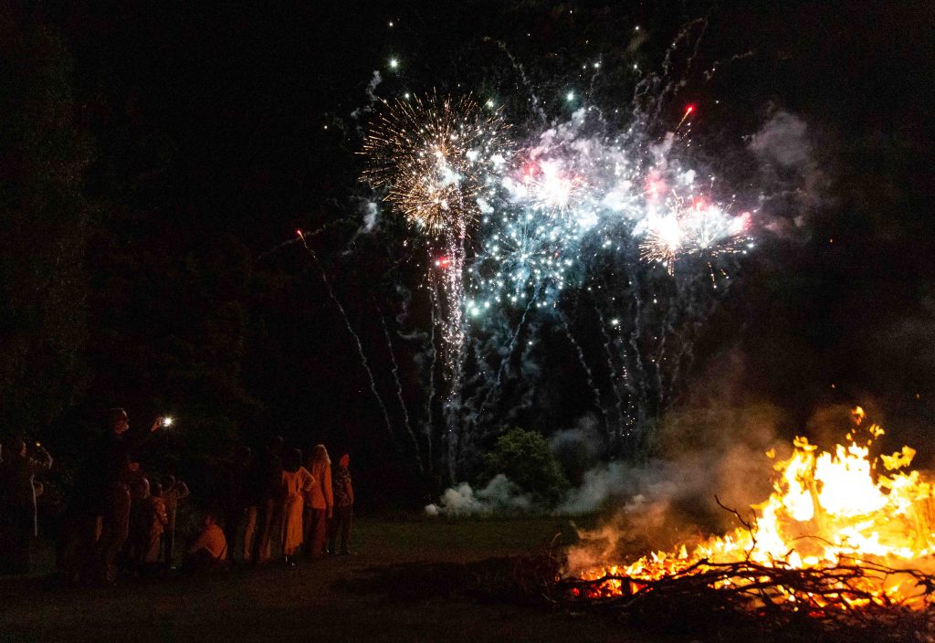 Fireworks exploding above a bonfire