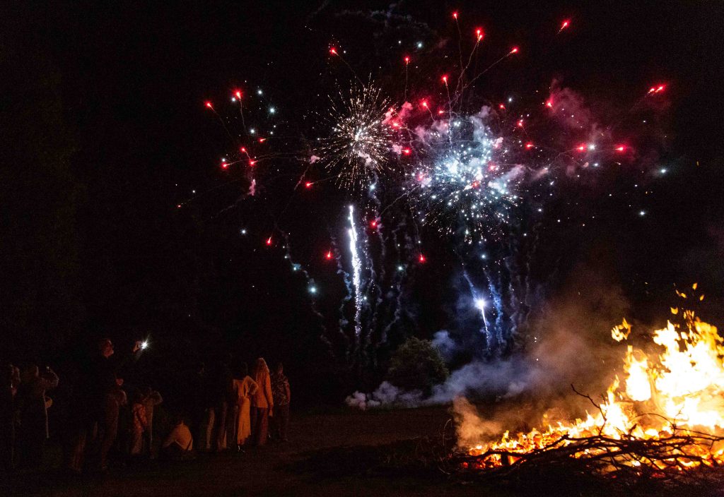 Fireworks in a night's sky over a bonfire