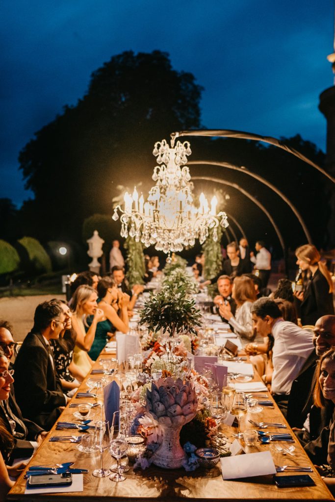 Dinner party guests under white chandeliers