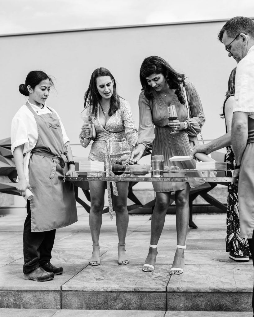 Black and white photo of a group of people interacting around food