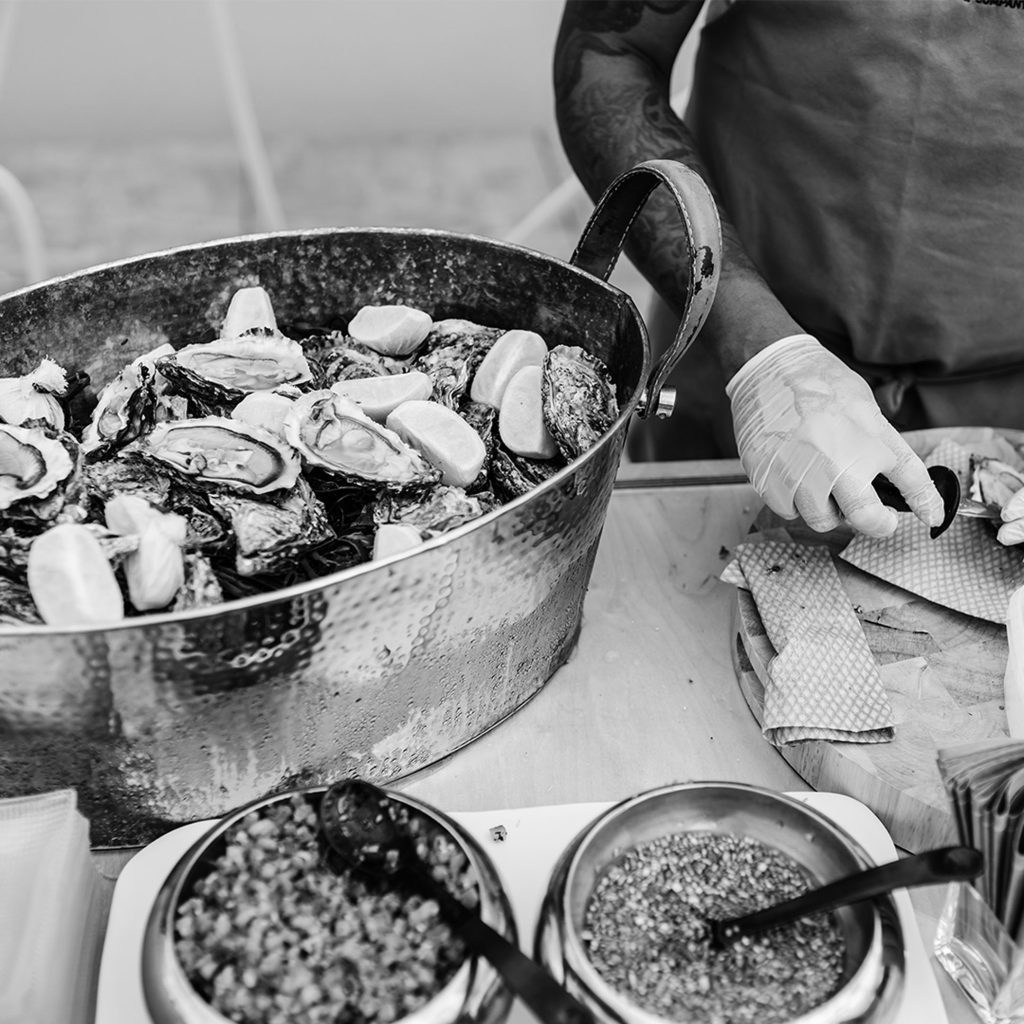 An oyster shucker and oysters in a large silver bowl