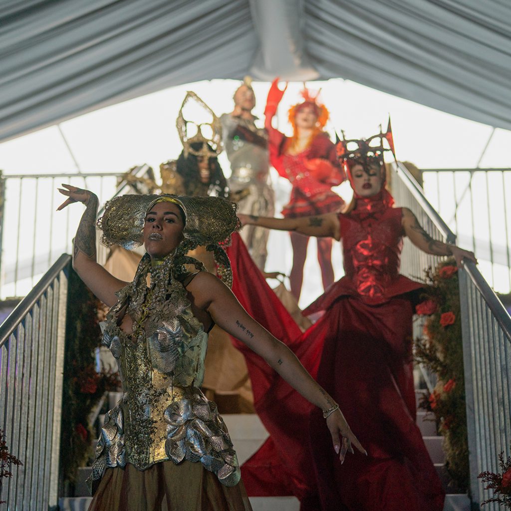 Actors in surrealist costumes on a metal staircase.