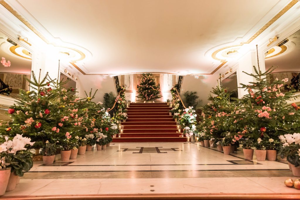 A grand staircase dressed with Christmas trees lit with lights and lanterns.