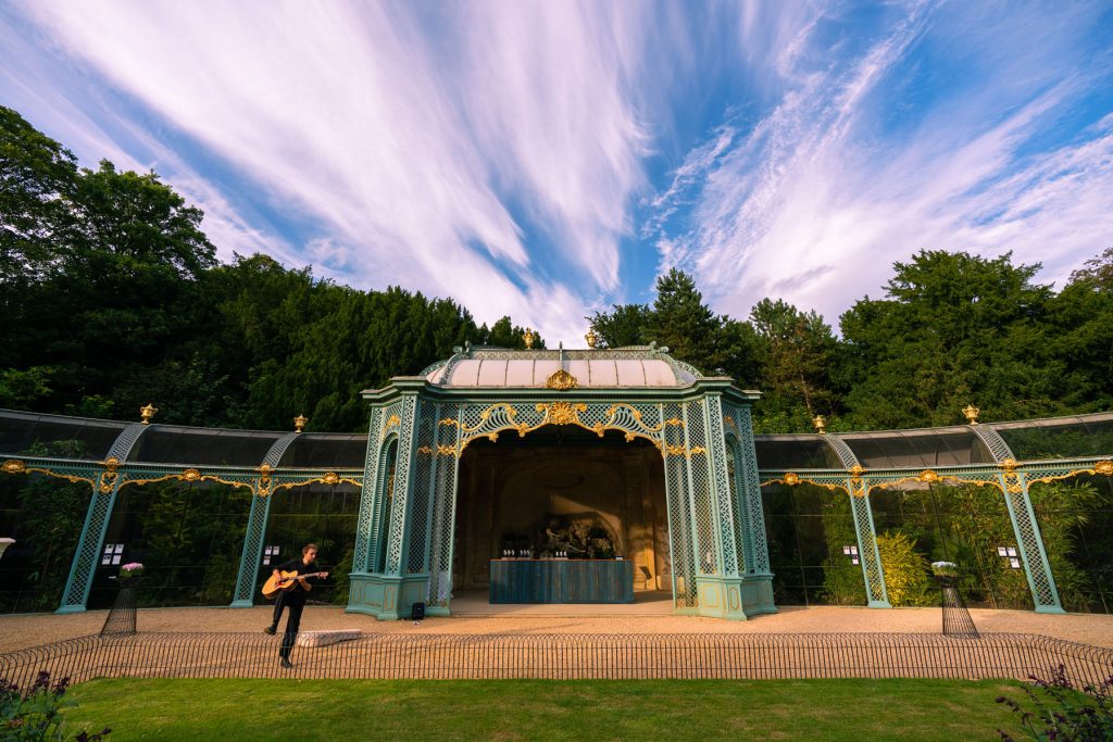 The Aviary at Waddesdon Manor and a guitarist performing on the gravel path.
