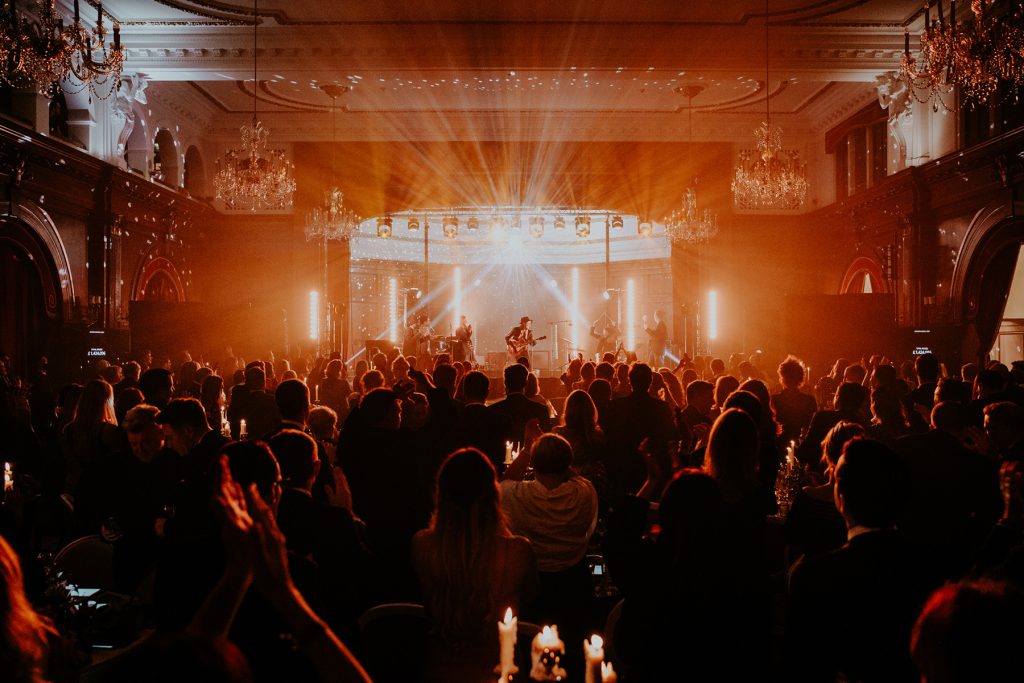 A stage lit in amber light and a crowd in the foreground.