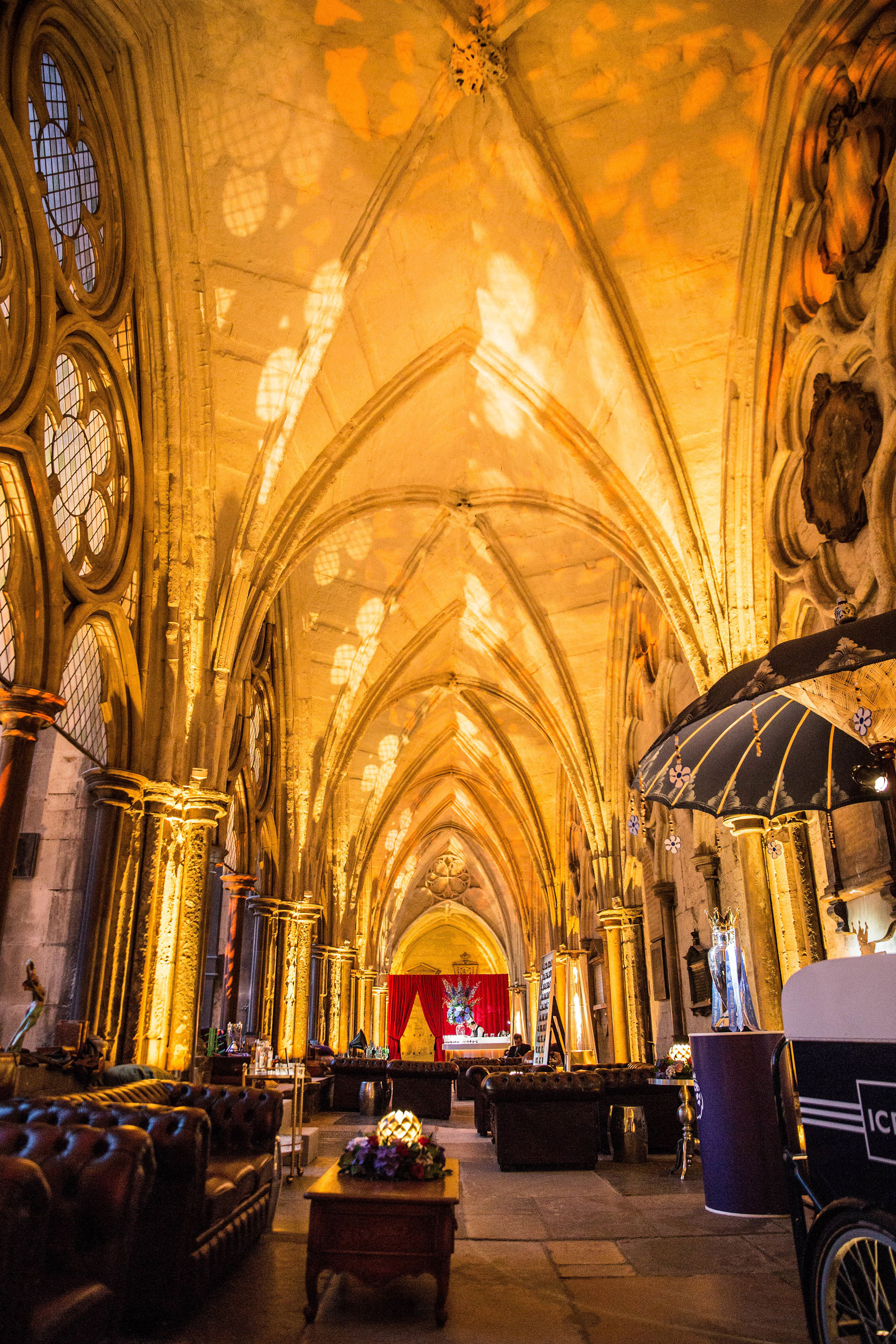 The Cloister of Westminster Abbey lit in amber lighting with furniture and props