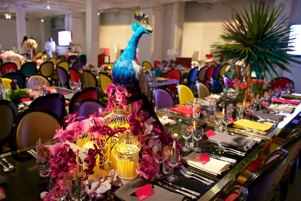 A peacock set on a table full of various props.