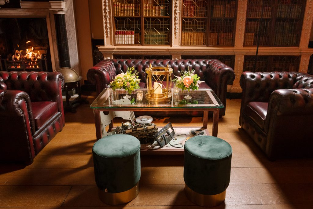 A cluster of blood ox red Chesterfield sofas, a glass coffee table and green ottoman stools.
