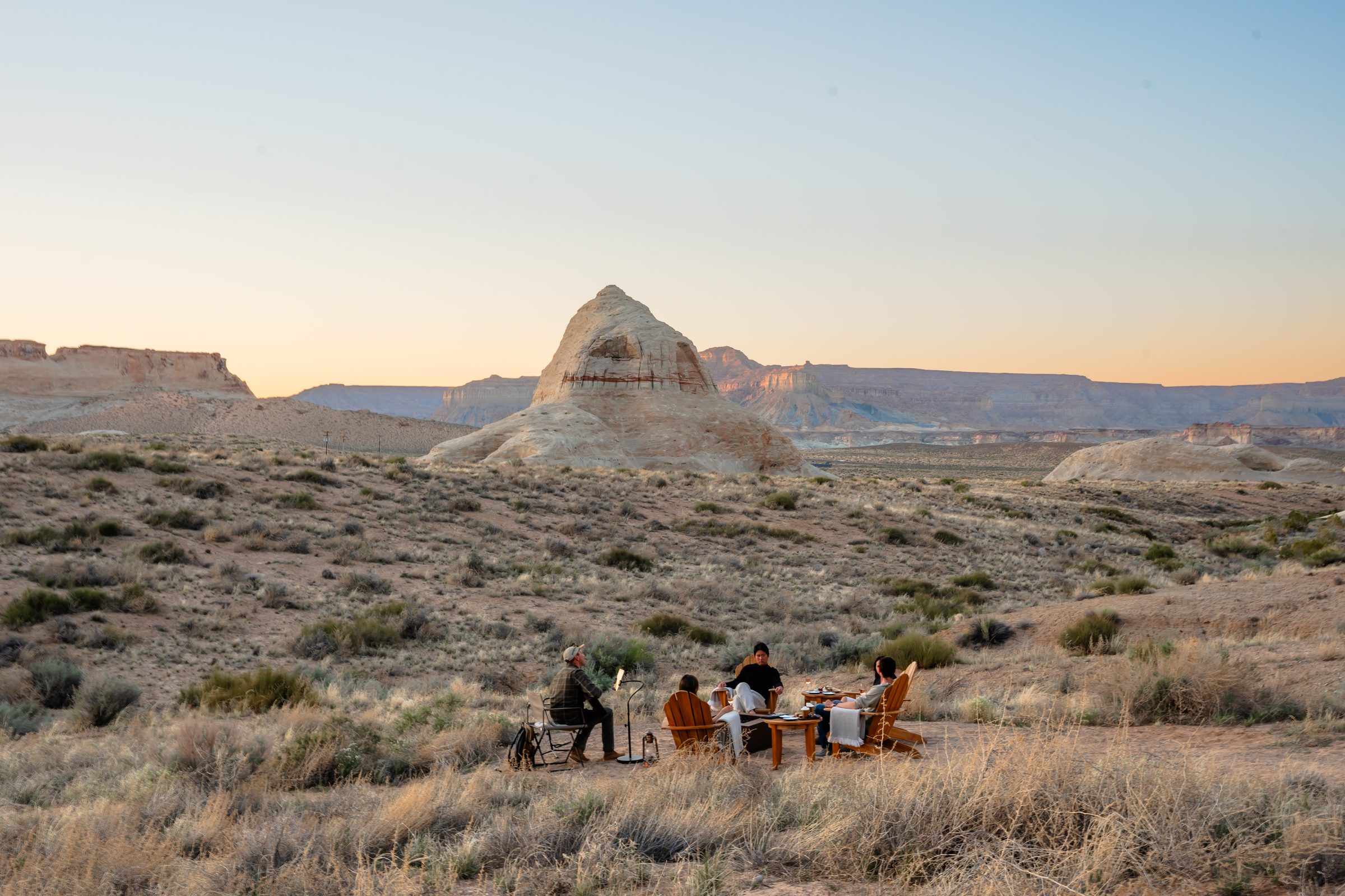 A small dinner table set in the Utah desert at dusk, mesas on the horizon