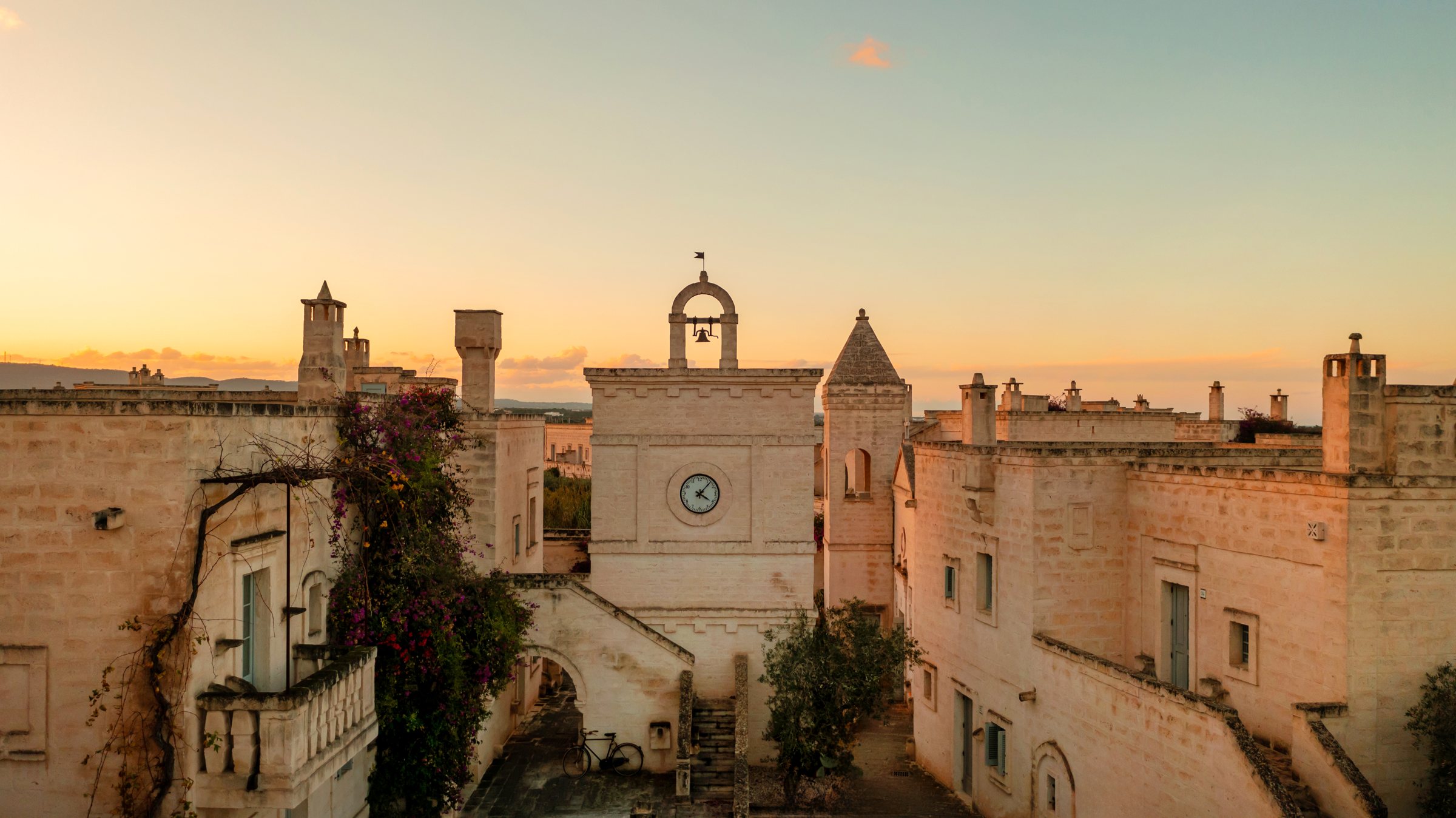 The clock tower over the rooftops at sunset.