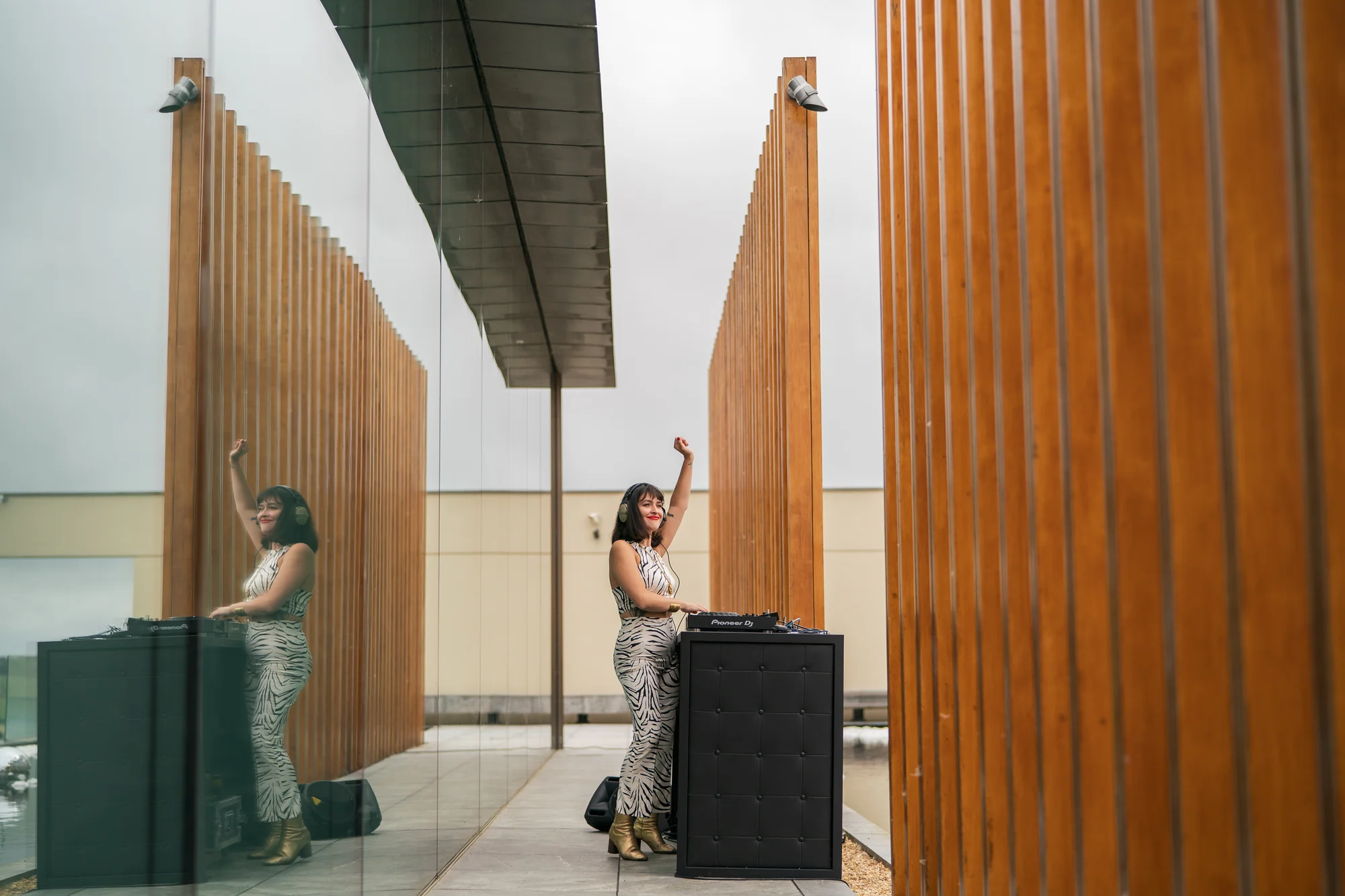 Tall timber fins on the terrace with a speaker stack set between them and a guest walking past.