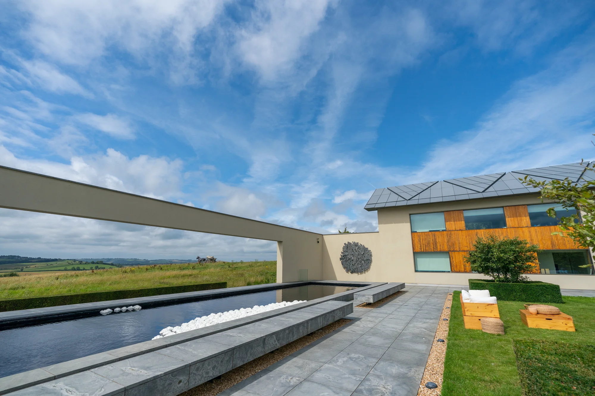 The long low building at Windmill Hill with its reflection pool running out in front of it under a wide summer sky.