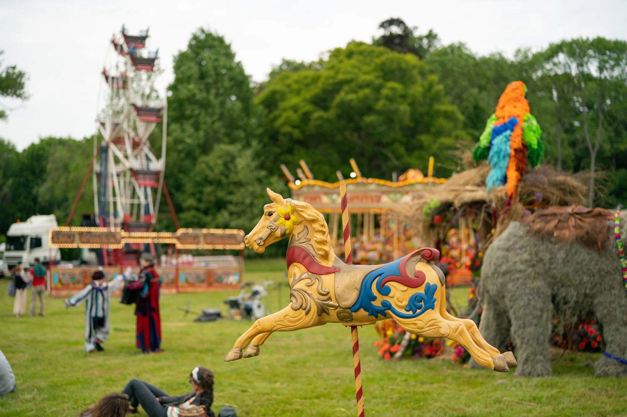 The funfair across the pasture, a carousel horse in the foreground with the helter-skelter and a straw elephant beyond.