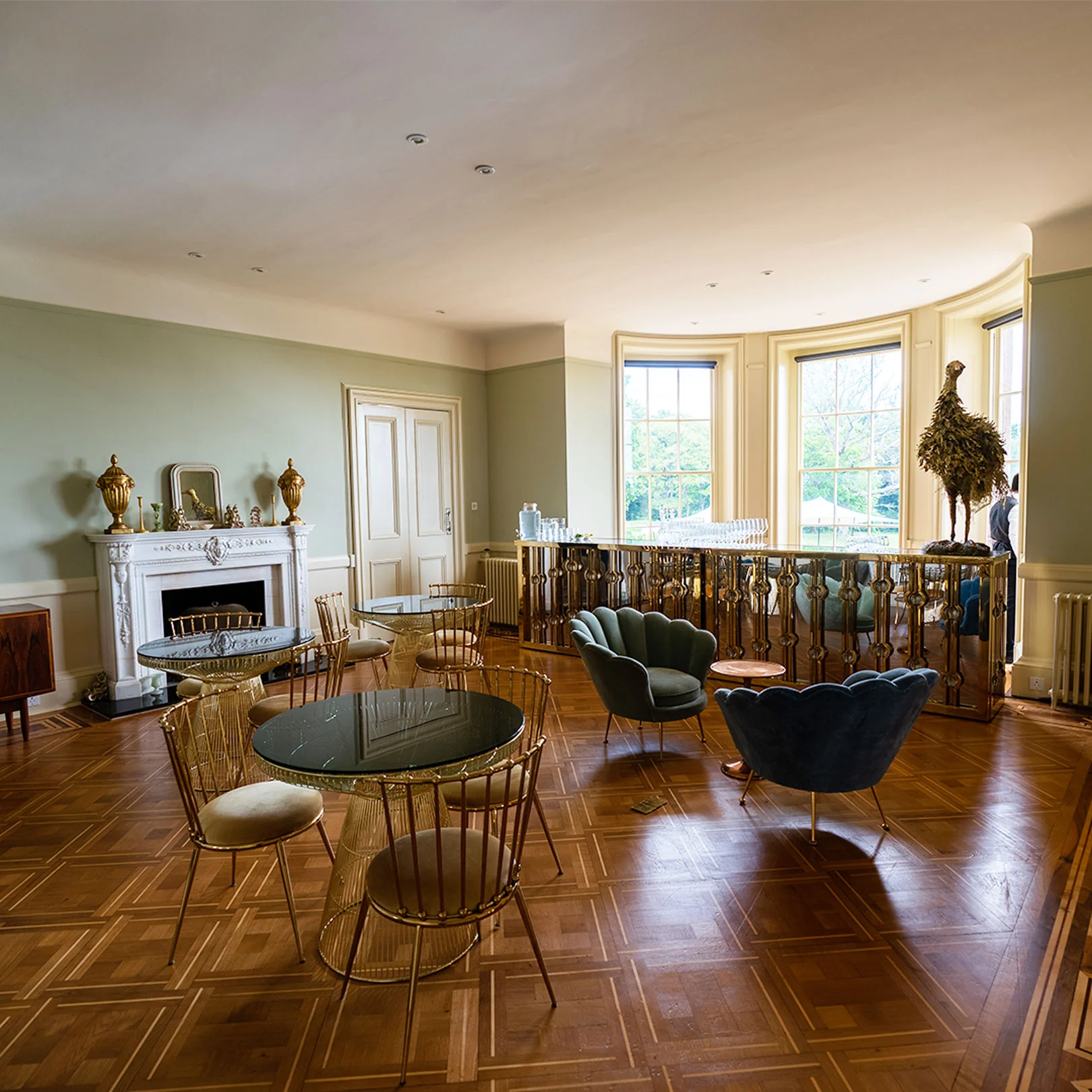 The cocktail lounge inside the house, parquet floor, a marble fireplace and low seating in the curved bay window.