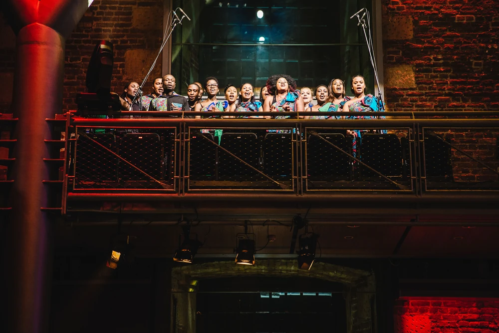 A choir singing from the iron balcony that runs round Jerwood Hall.