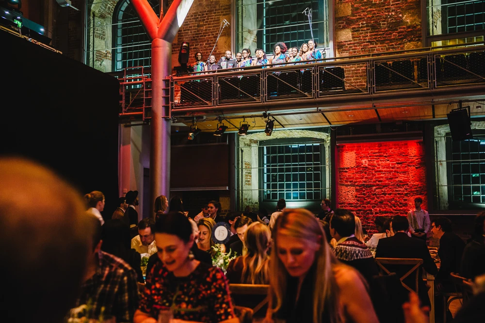 Guests talking at their table with the brick arches of the hall behind them.