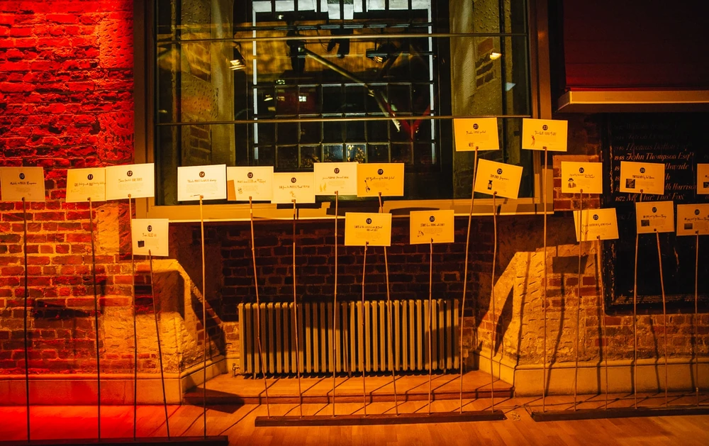 Seating cards hung on wires against the exposed brick wall at LSO St Luke’s.