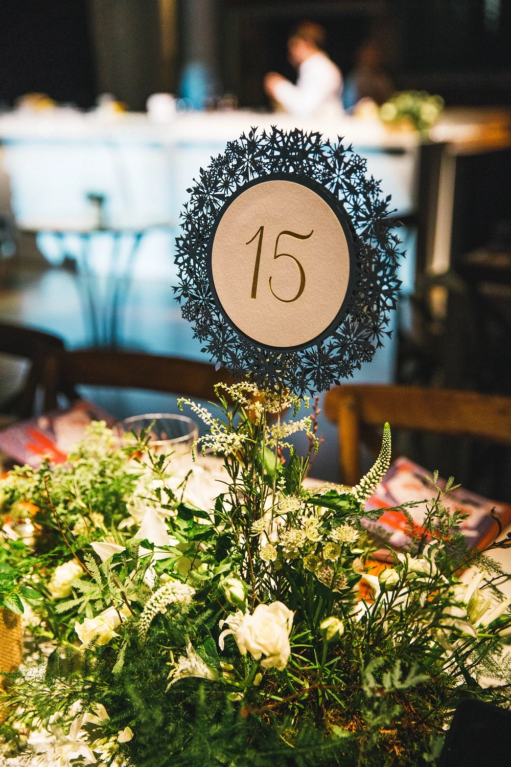 A table number set in a wreath of foliage on a dressed table.