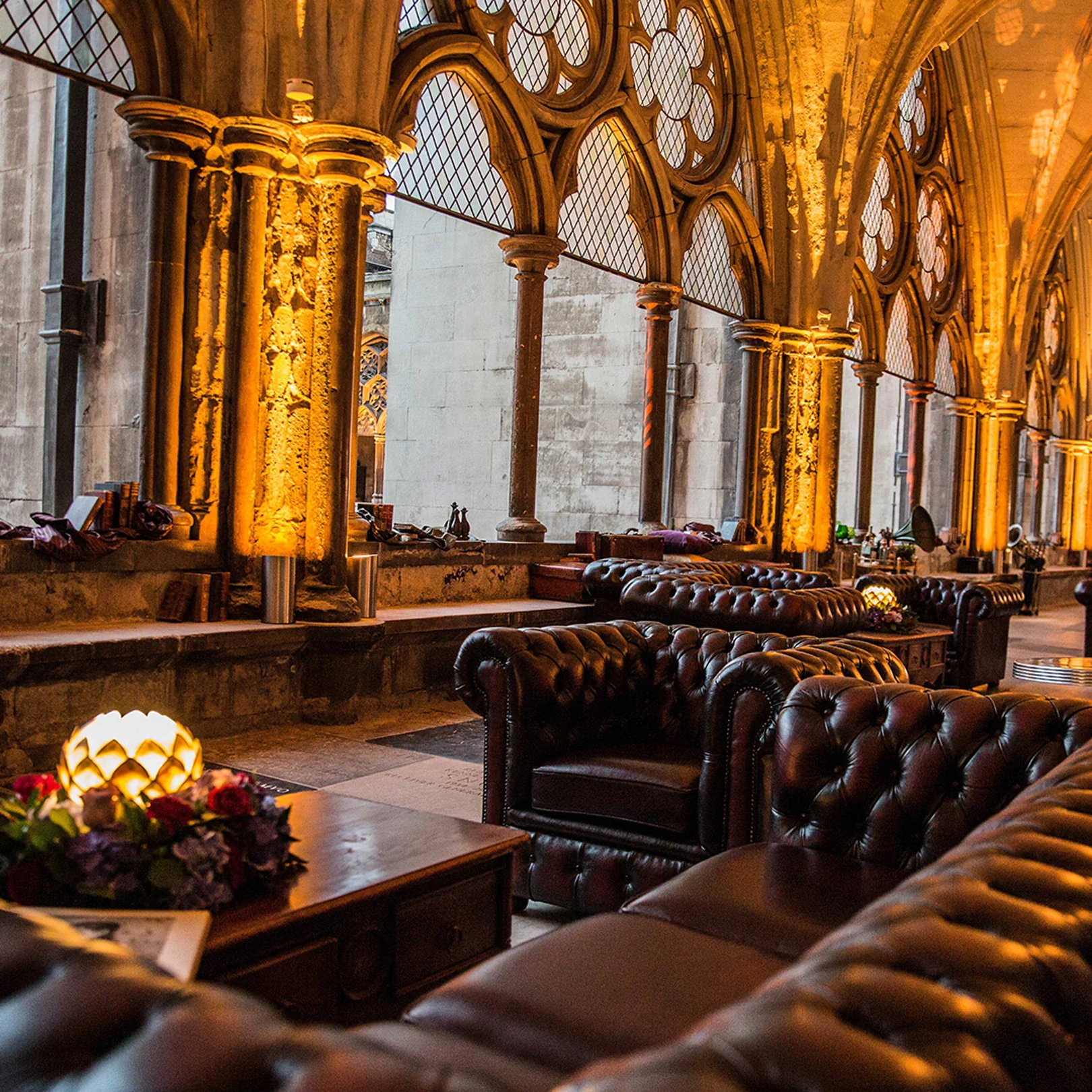 Buttoned leather chesterfields and low tables set out along the gilded arcade, candles lit on the tables.