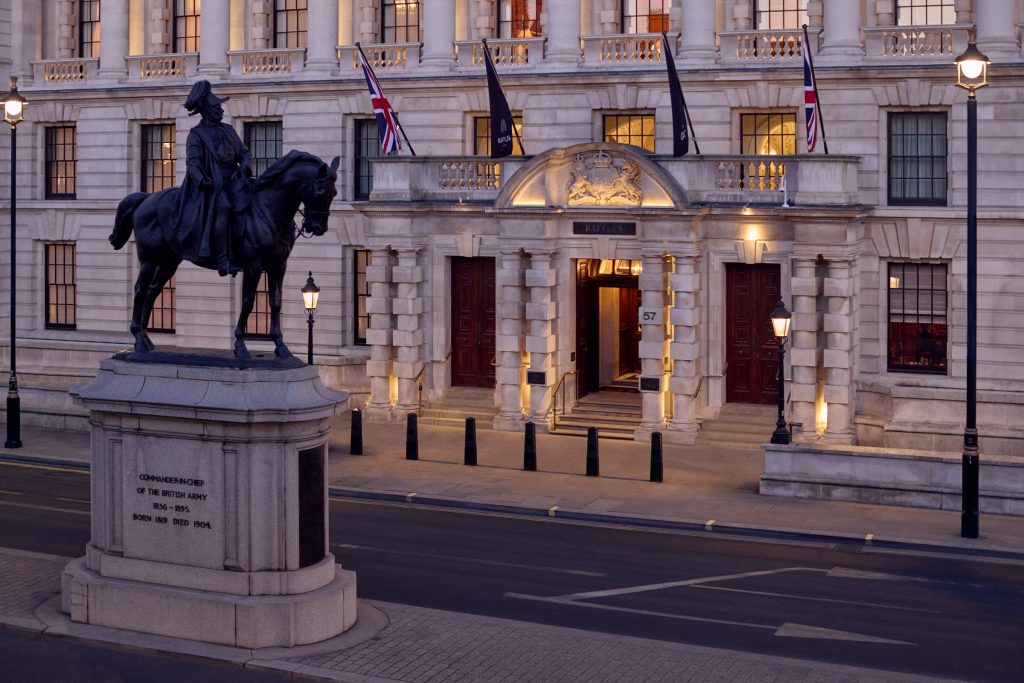 The Whitehall façade of Raffles London at The OWO at dusk, with the equestrian statue in front.