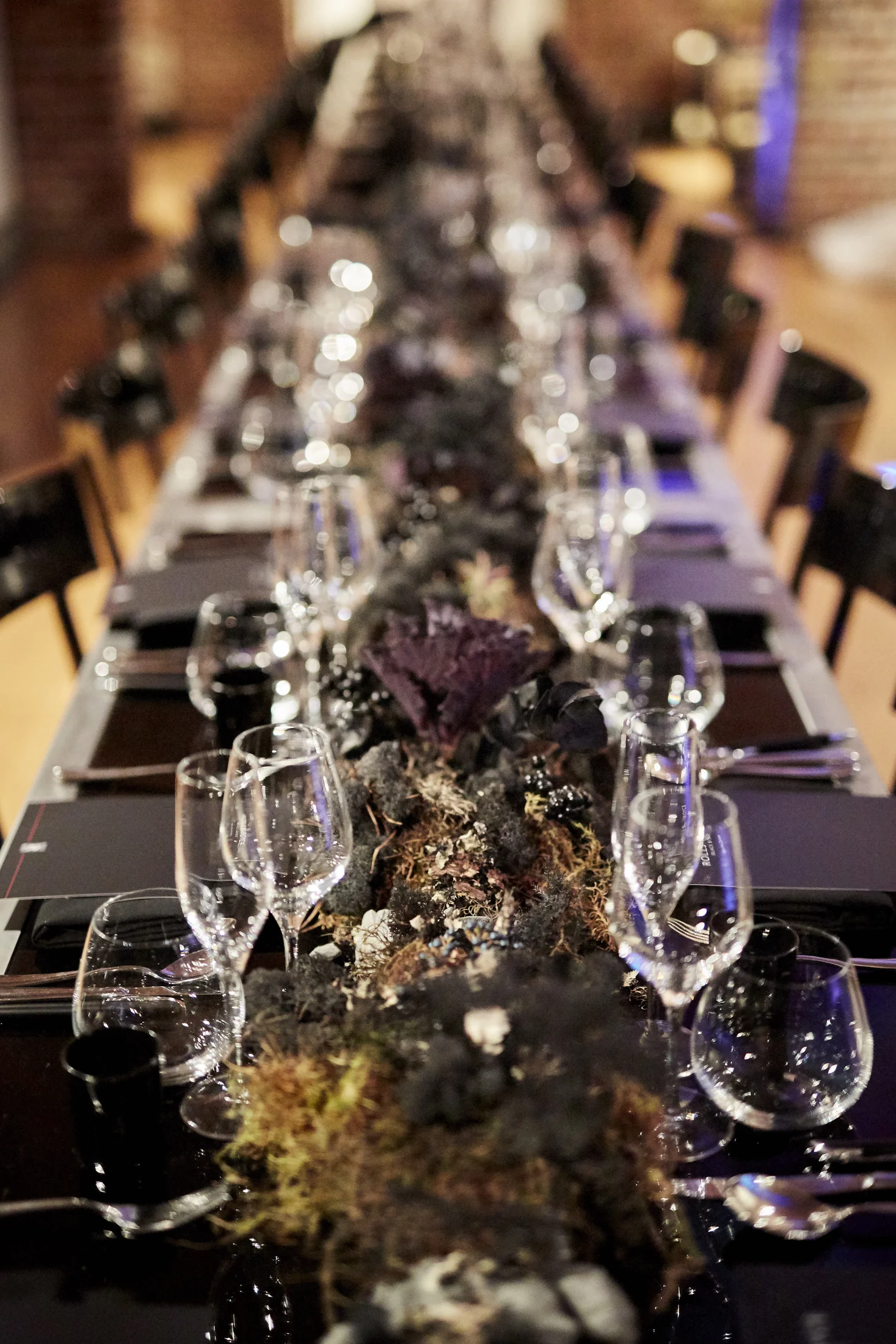 The table from one end, glassware and runner running away into the dark of the vault.