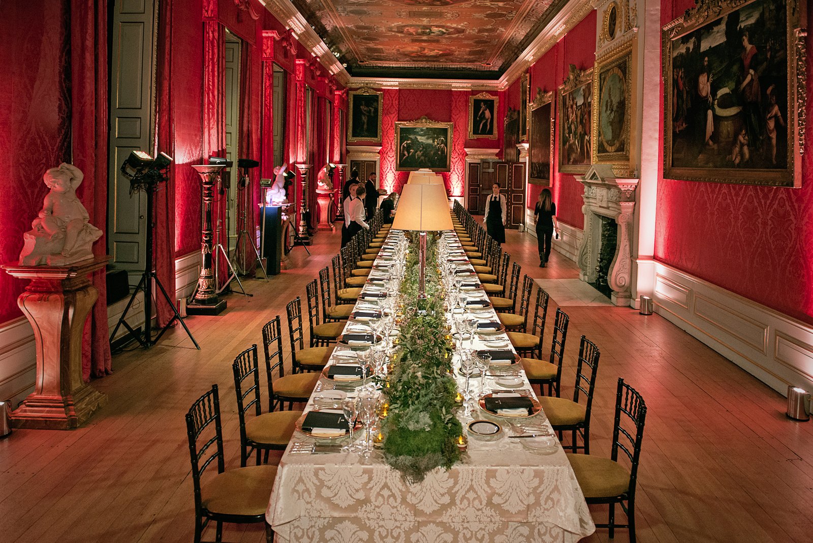 A long table laid down a red damask gallery hung with Old Master paintings