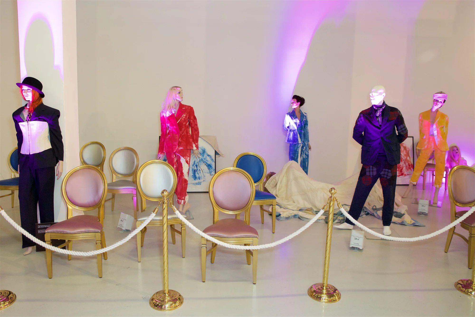 A red carpet catwalk laid between rope barriers, mannequins in vulgar dress standing along both sides of it.