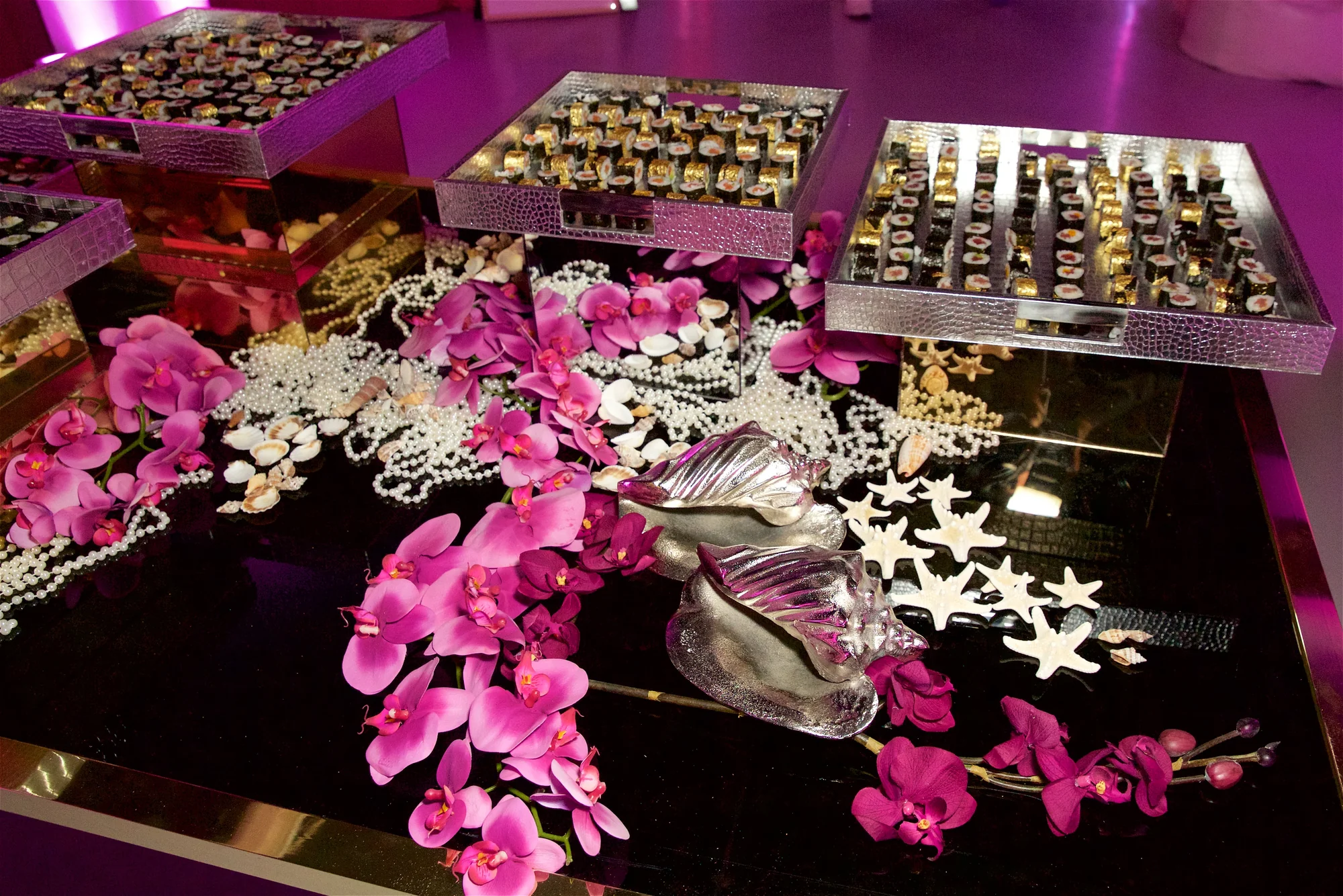 A table laid with boxes of chocolates, pink orchids and strings of pearls.