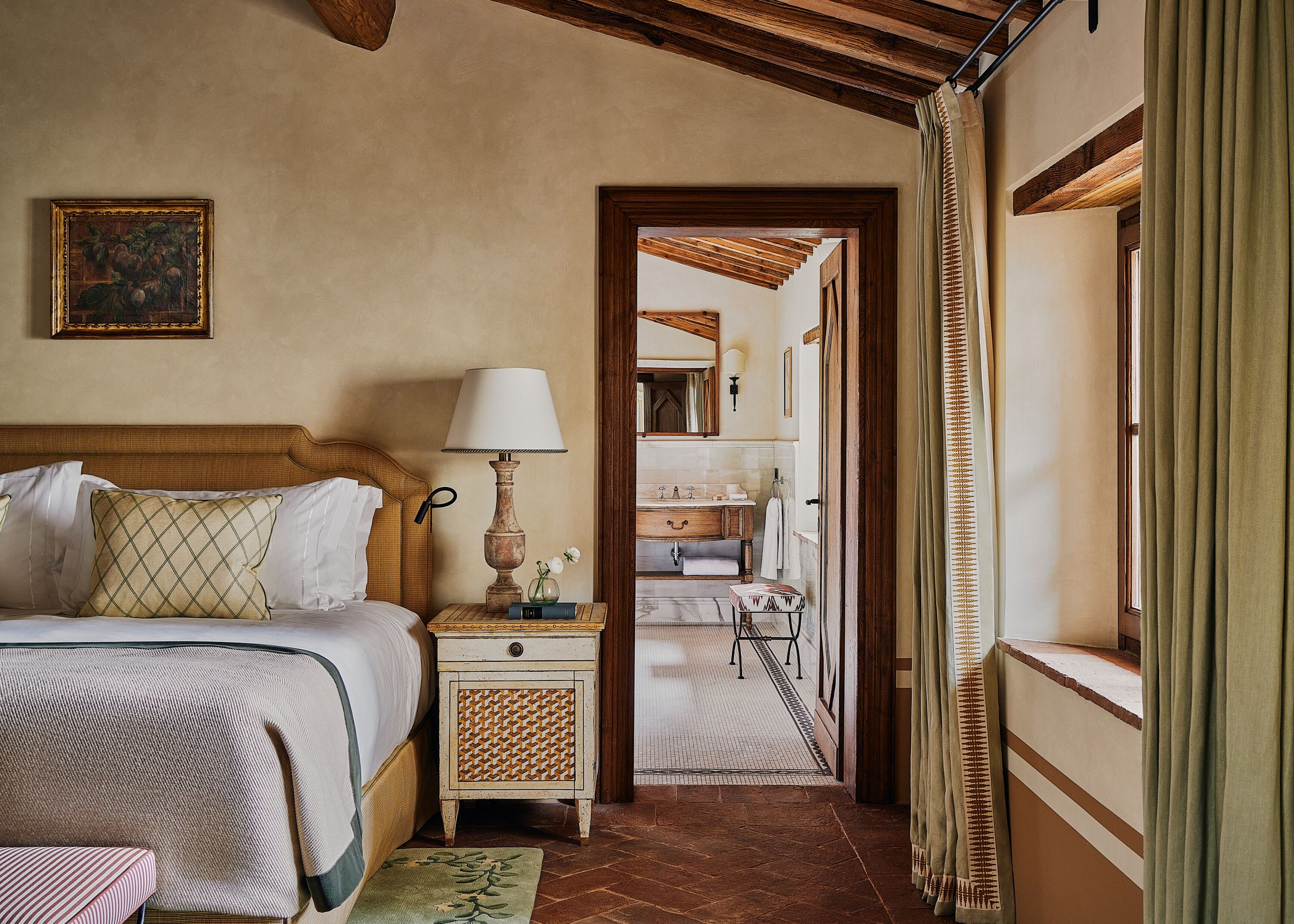 A suite bedroom at Castello di Casole with a view through to the bathroom.