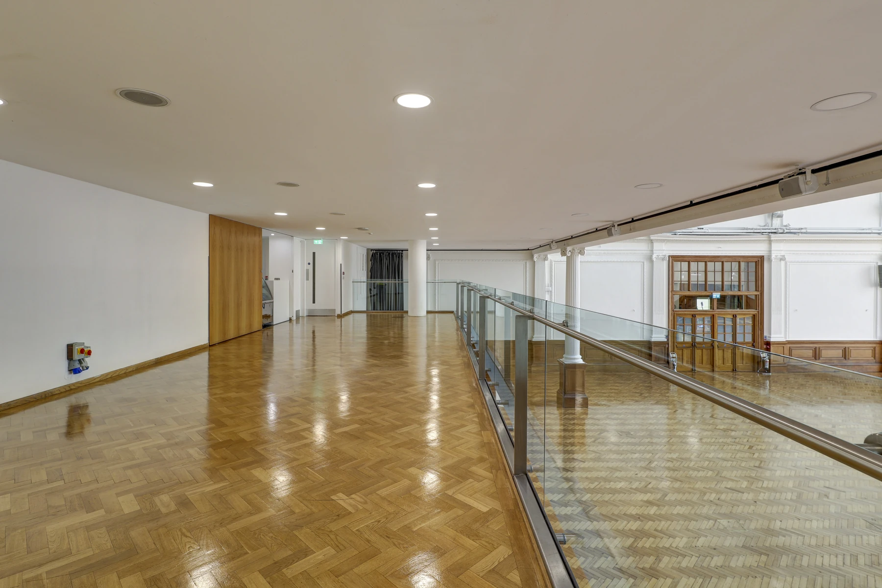 The Mezzanine Balcony at Lindley Hall, a parquet gallery with a glass balustrade looking down onto the Main Hall.
