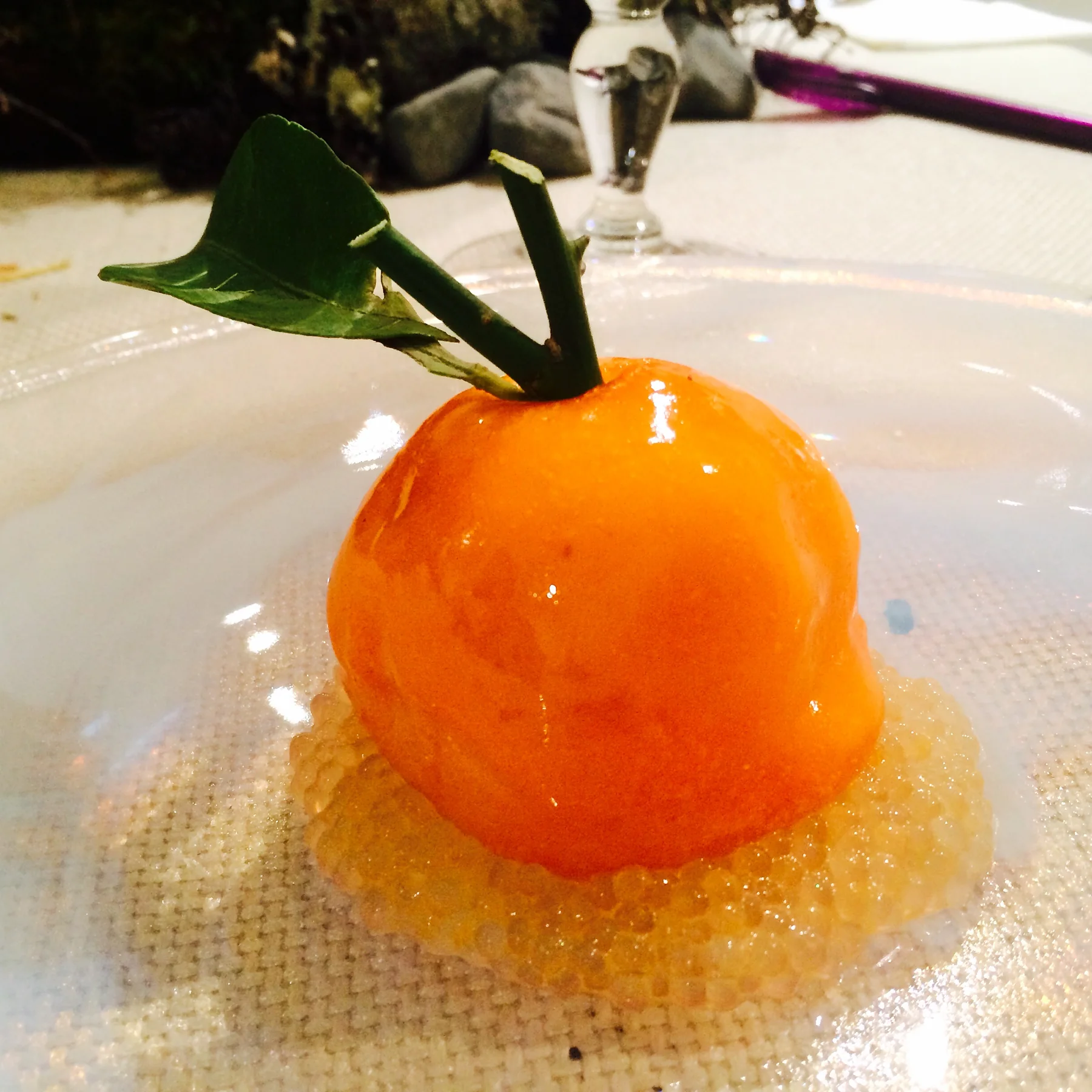 The passion fruit and mandarin jelly, round and lit, set on the plate.
