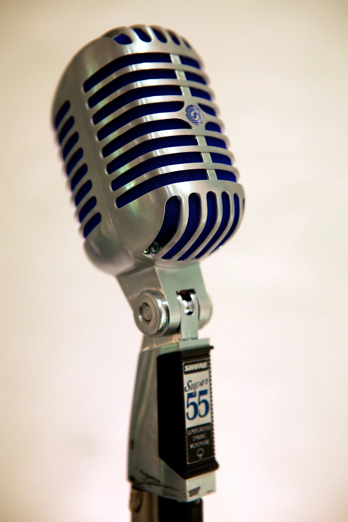 A vintage chrome microphone against a pale ground.