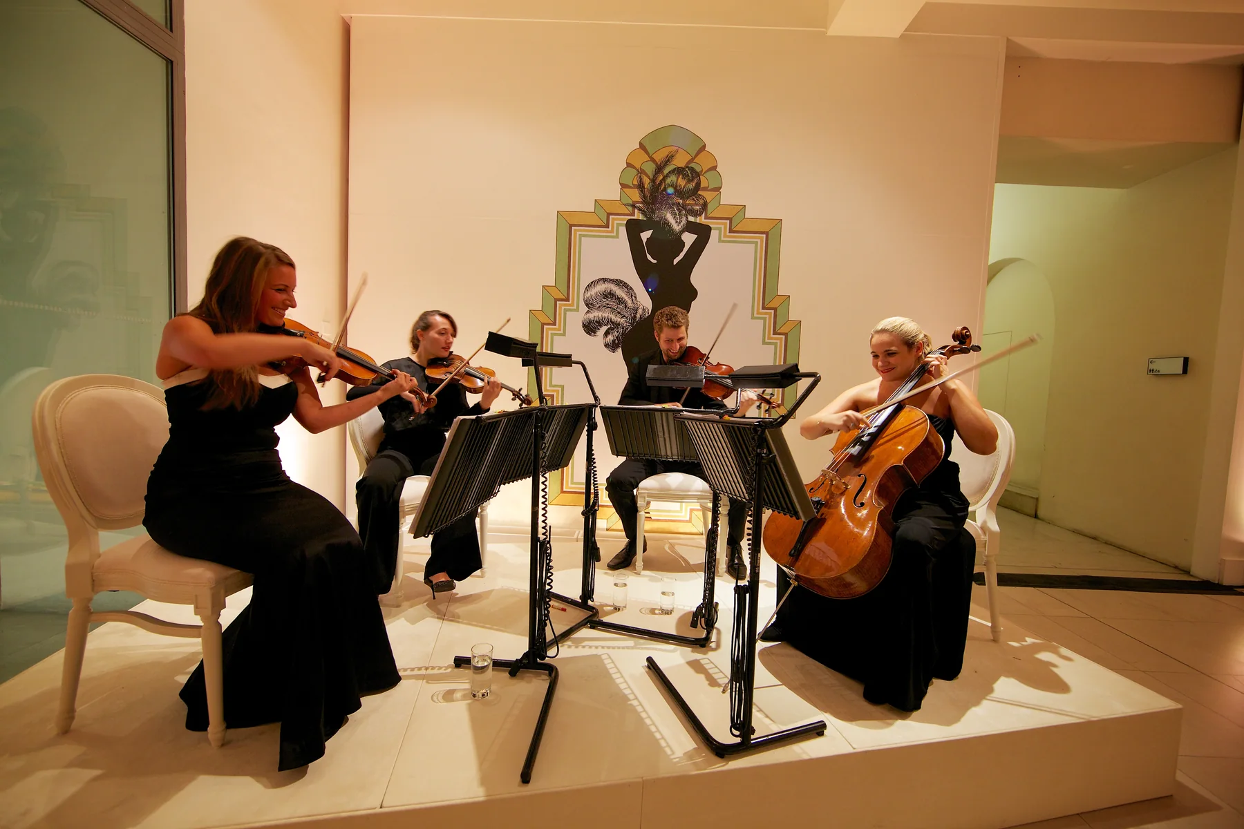 The string quartet seen wider, the room glowing amber around them.