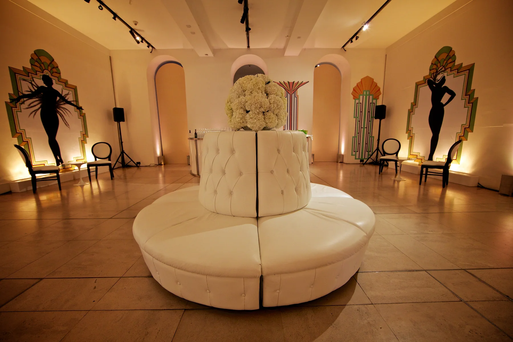 The circular banquette in place with the flower ball above it and the dancer panels lit behind.
